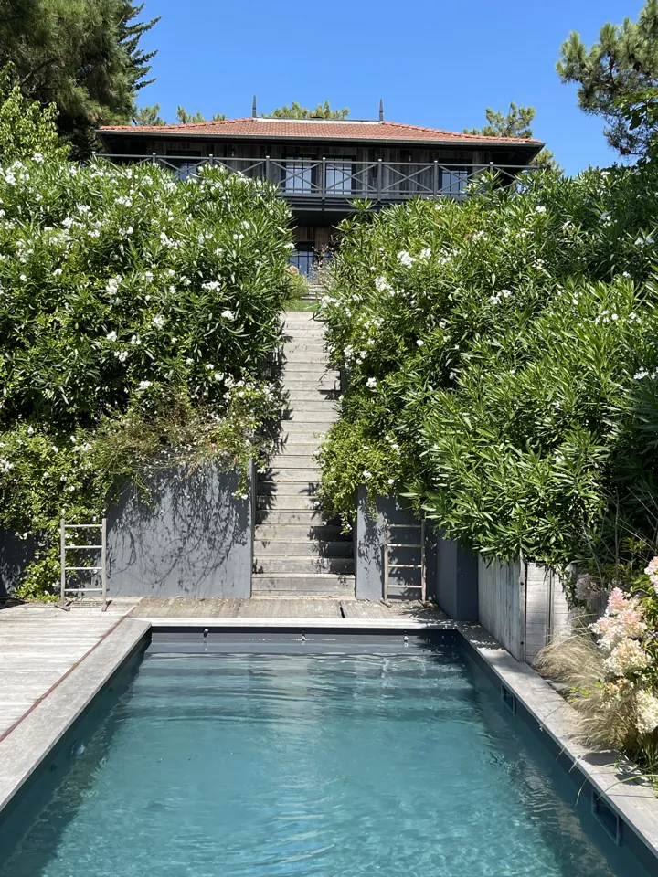Piscine au pied d’une maison en bois surélevée